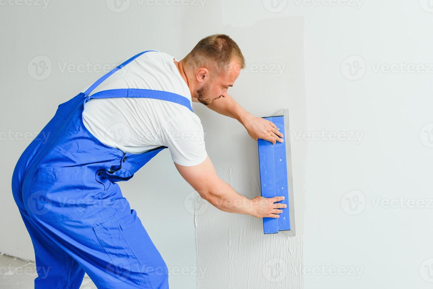A man processes the wall with a spatula. Plasterer at work. photo