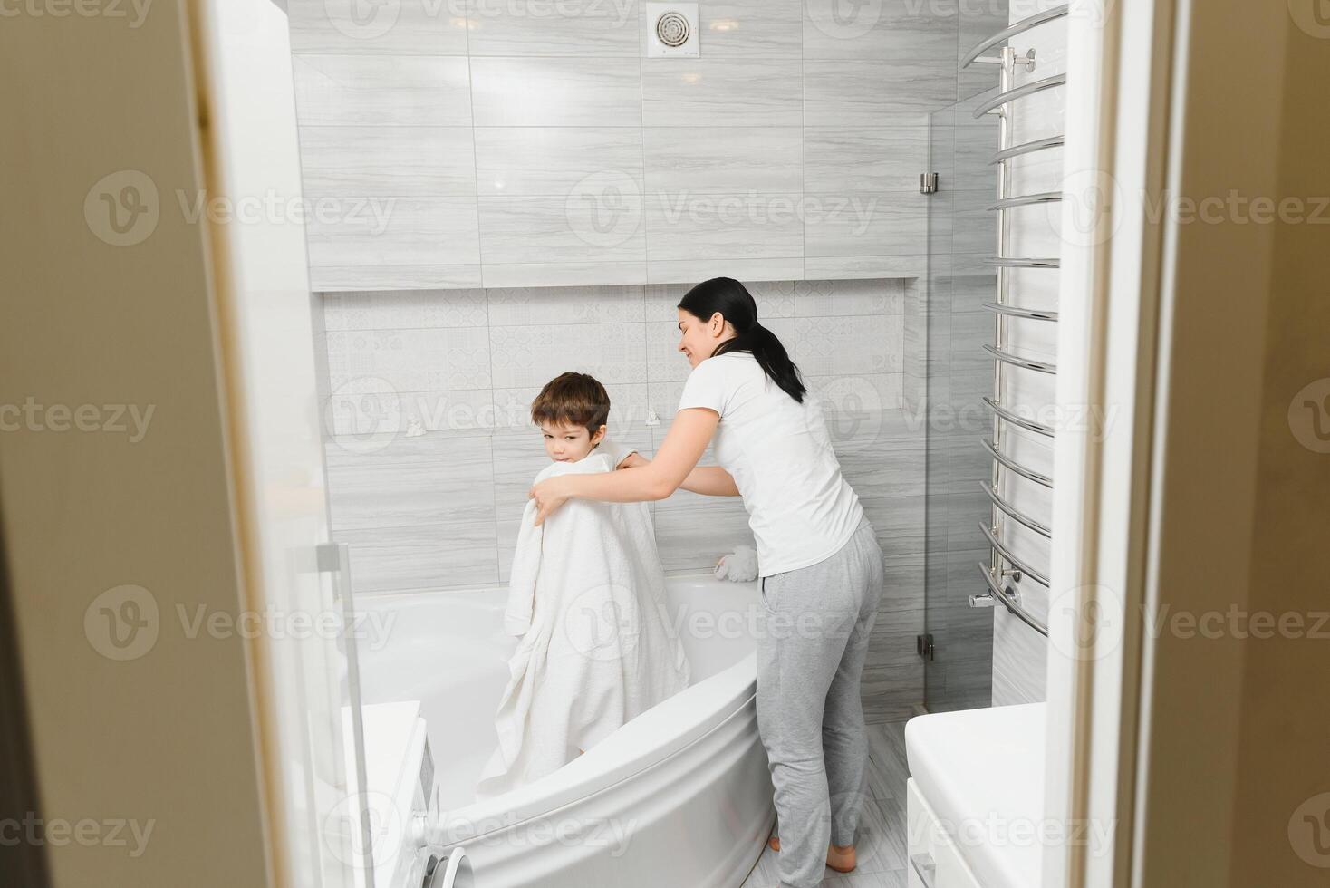 Mother washing little son in bathroom photo