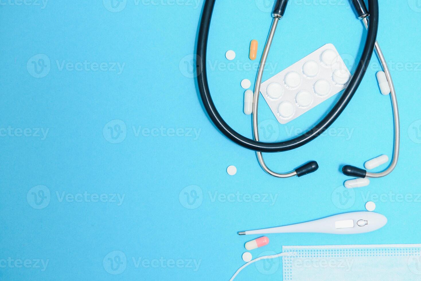 dispersado blanco pastillas en azul mesa.medica, farmacia y cuidado de la salud concepto. azul antecedentes blanco pastillas con un médico estatoscopio, parte superior ver foto