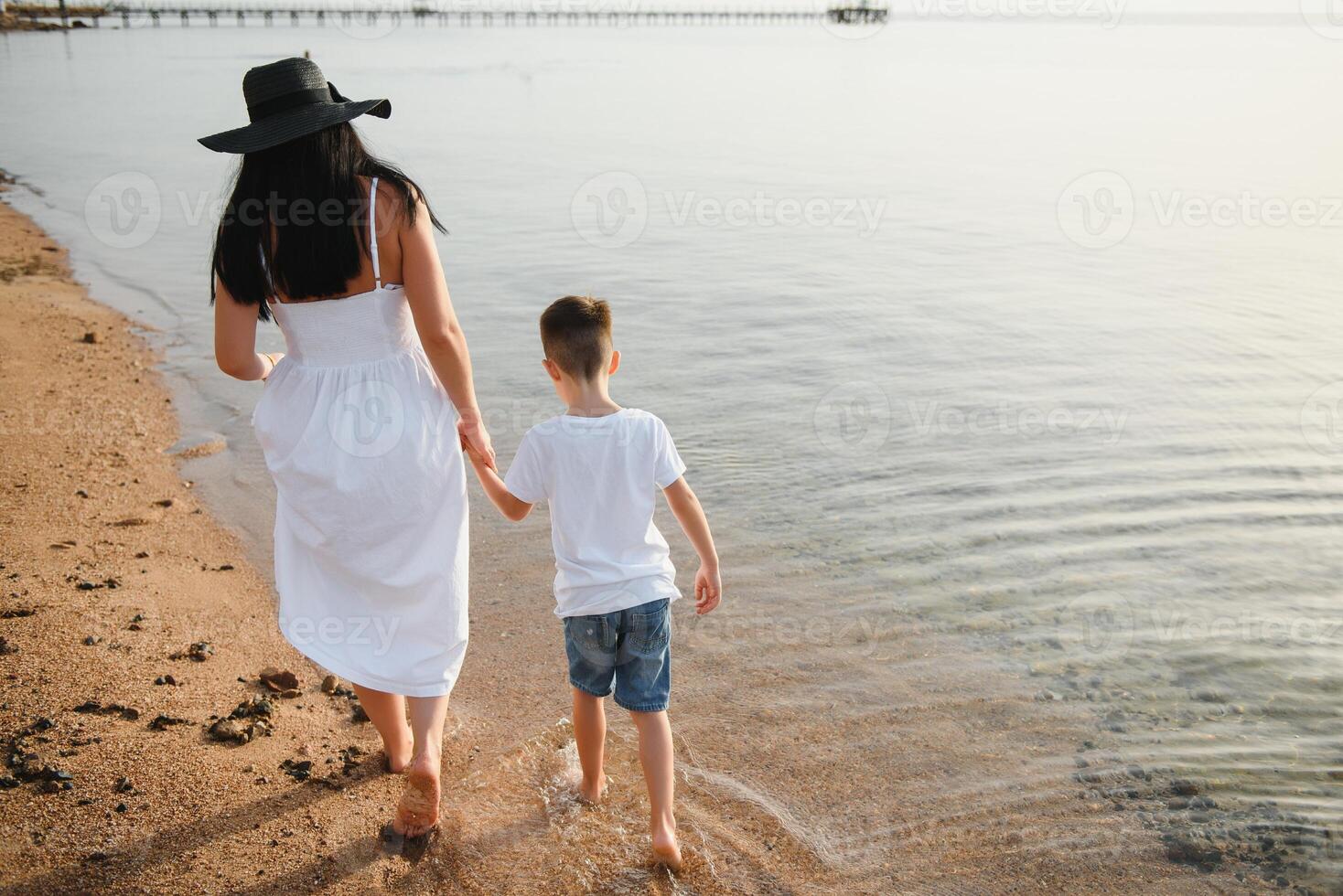 Mother and son playing on the beach at the day time. Concept of friendly family. photo