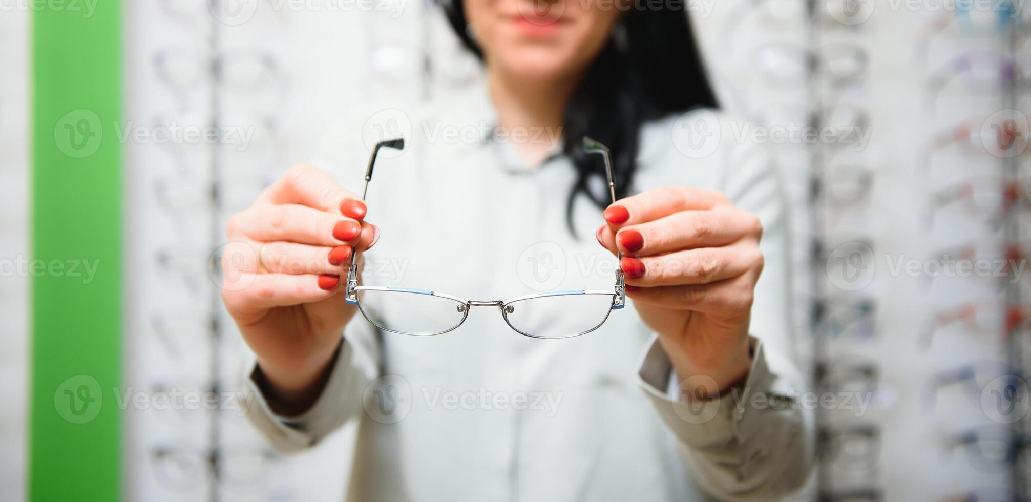 Closeup of optometrist, optician giving glasses to try. photo