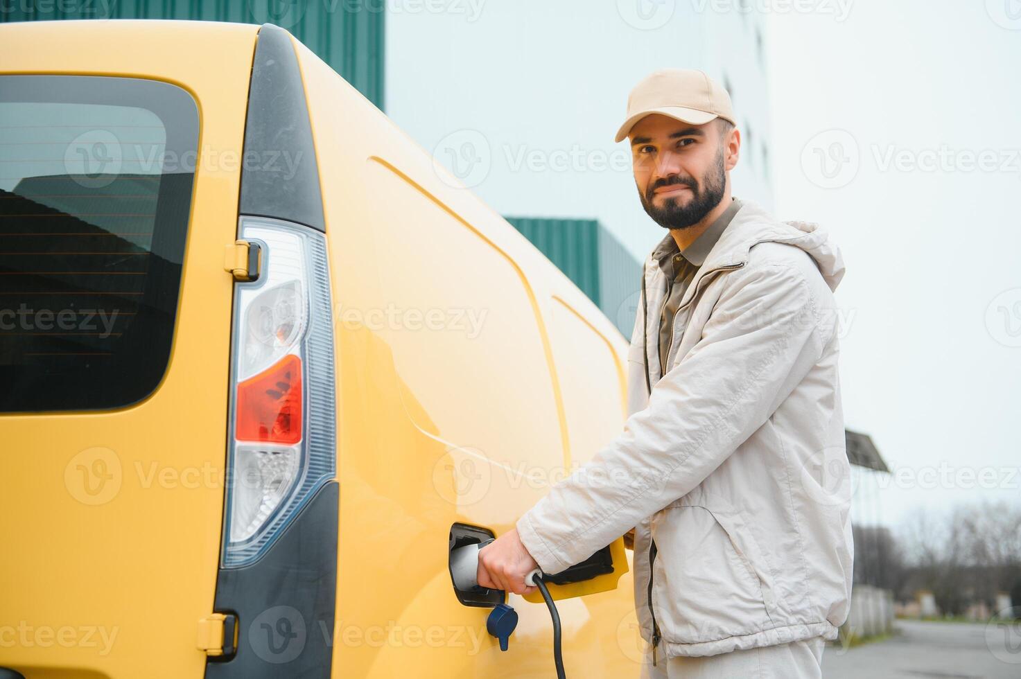 Casual man near electric car waiting for the finish of the battery charging process photo