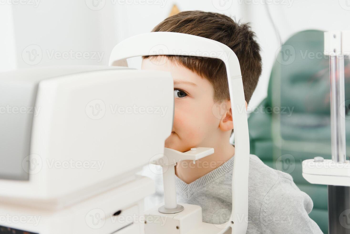 Optometry concept. Female optometrist optician doctor examines eyesight of child boy in eye ophthalmological clinic. photo