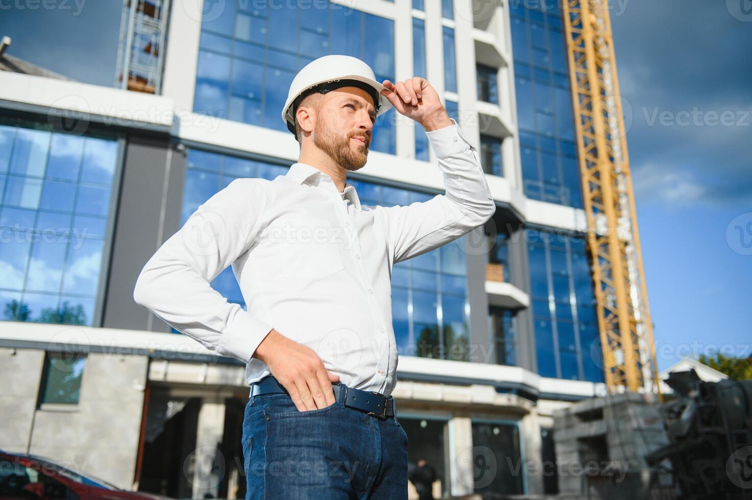 Engineer next to building cranes. Concept - large construction project. Architect directs the construction process. Drawings and tablet in the hands. photo