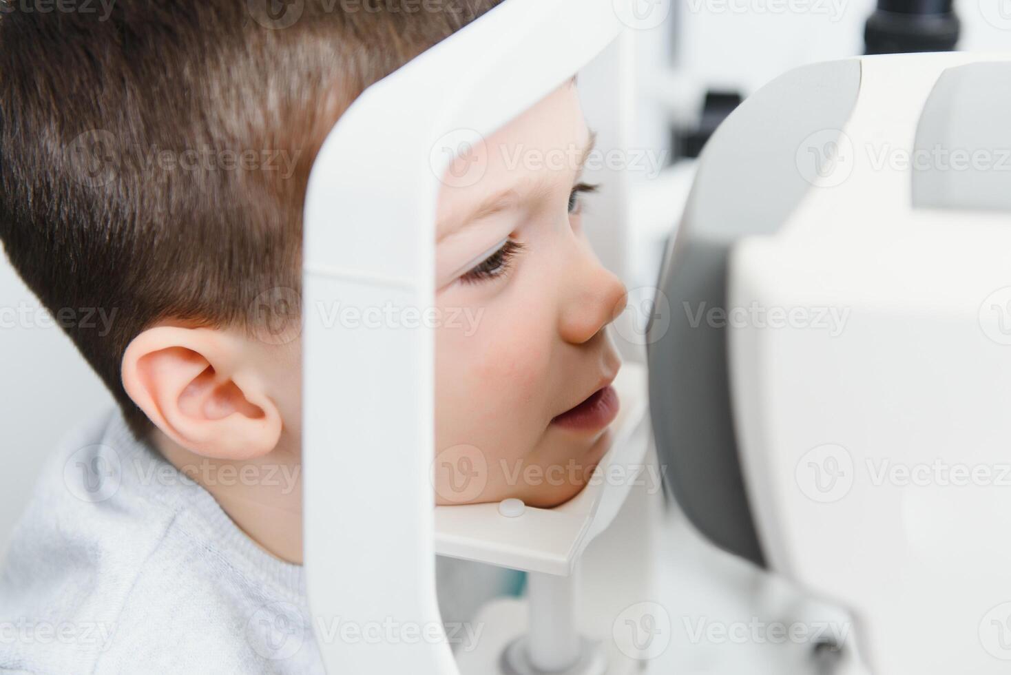 Optometry concept. Female optometrist optician doctor examines eyesight of child boy in eye ophthalmological clinic. photo