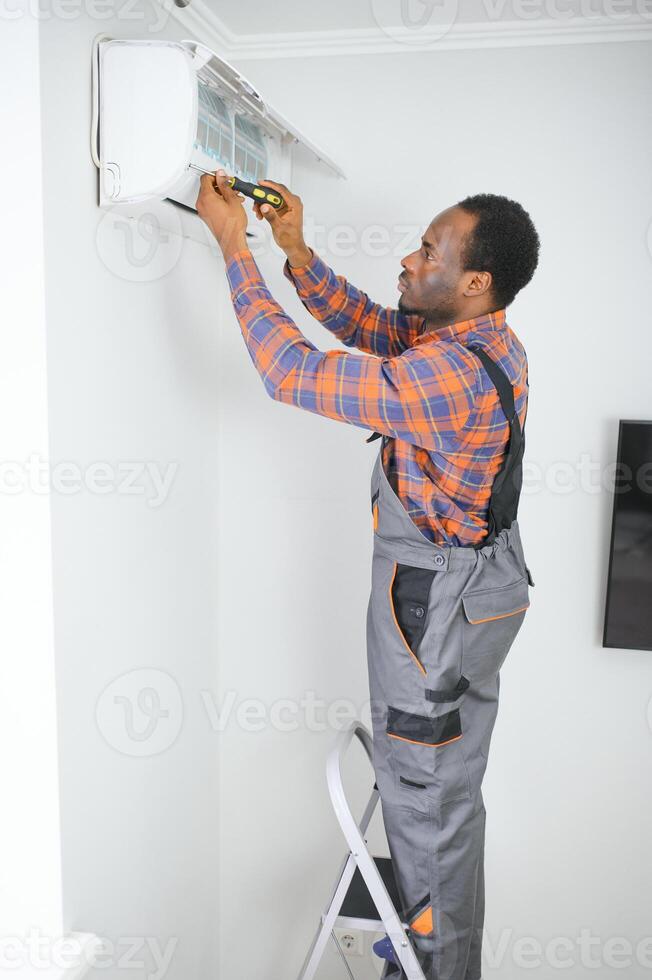 Professional repairman installing air conditioner in a room photo