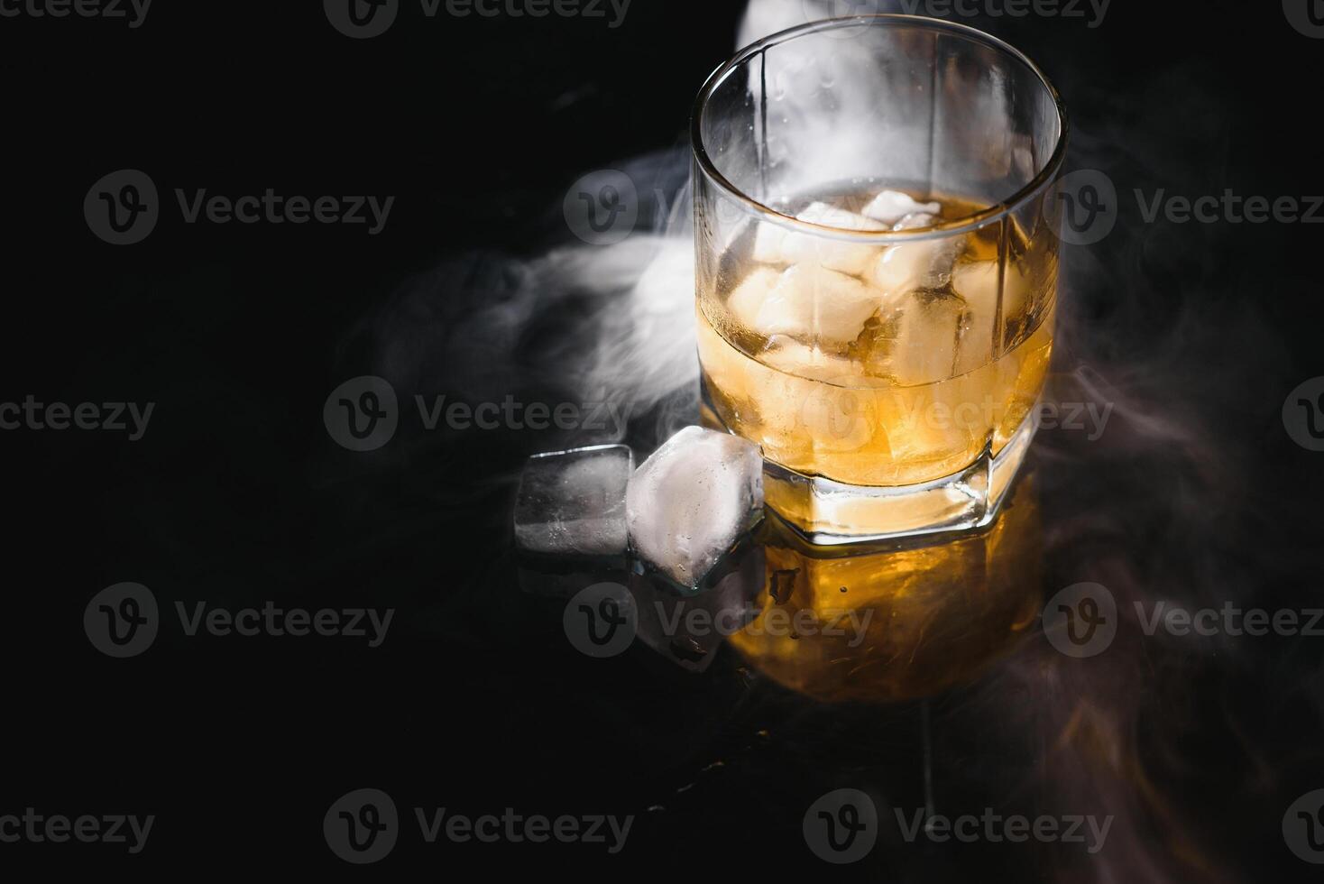 Glass of the whiskey with ice and a decanter isolated on a black background photo