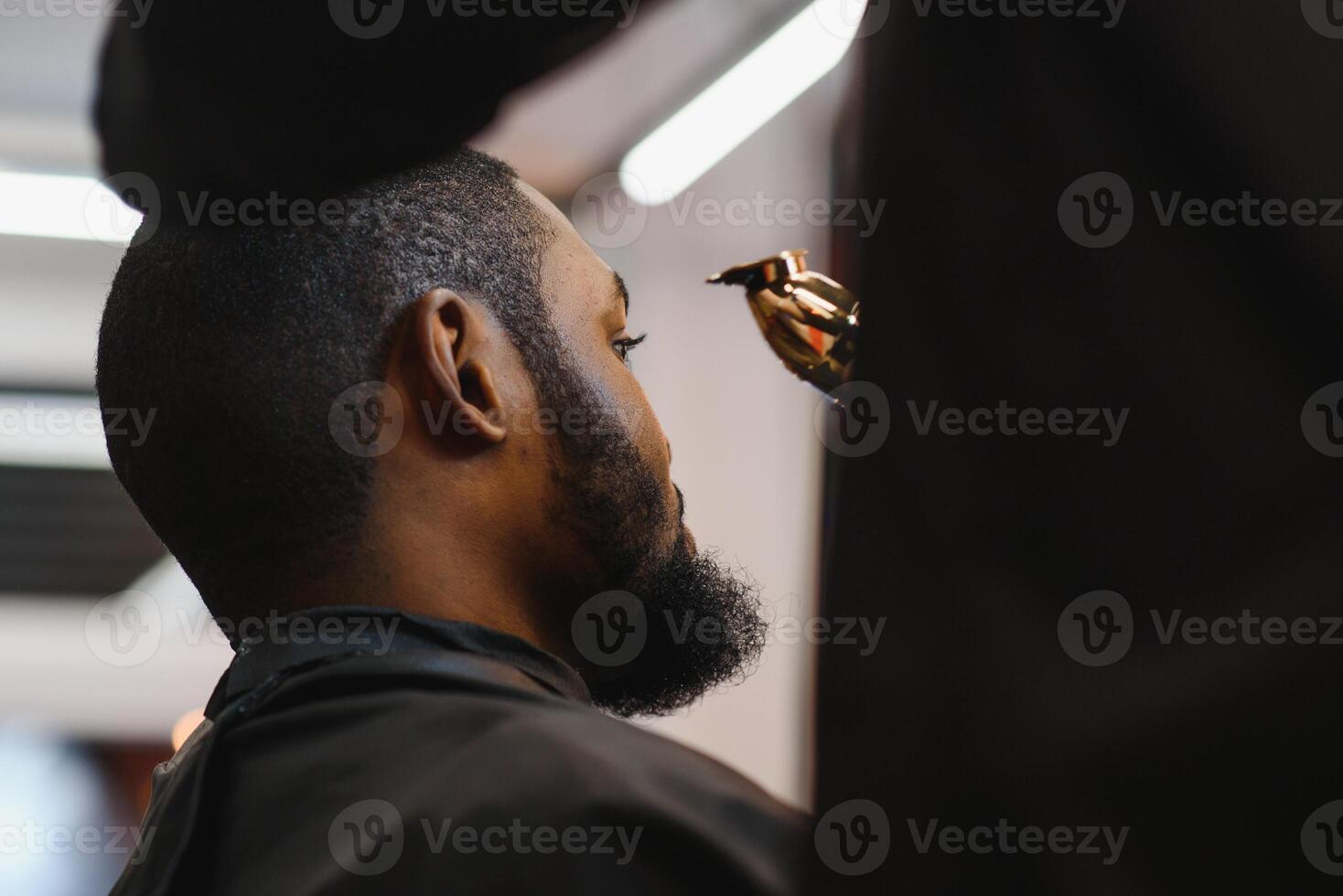 Closeup of process of trimming of hair in barber shop. Qualified barber keeping clipper in hands and correcting shape of hair to male client sitting on chair. Concept of haircut and shaving. photo