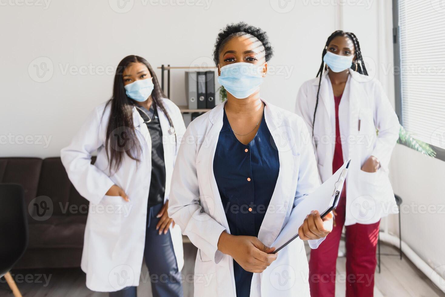 Group of healthcare workers wearing protective face masks while standing with arms crossed and looking at camera photo