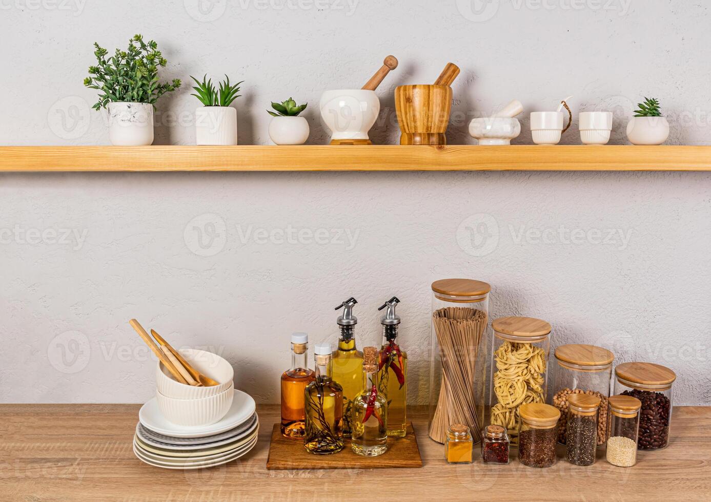 Stylish kitchen background with a set of bottles with various cooking oils, glass jars with spices. Front view of an open wooden shelf photo