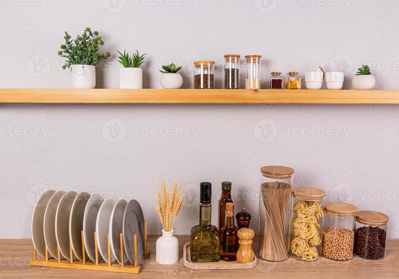 an open kitchen shelf and part of a wooden kitchen countertop with a set of containers for storing food and a dryer with plates. Front view. photo