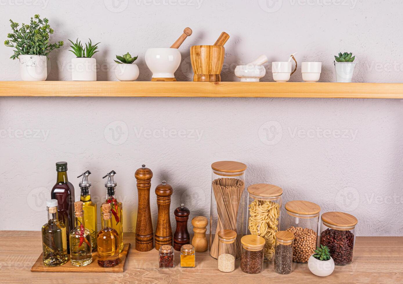 Stylish kitchen background with a set of bottles with various cooking oils, glass jars with spices. Front view of an open wooden shelf photo