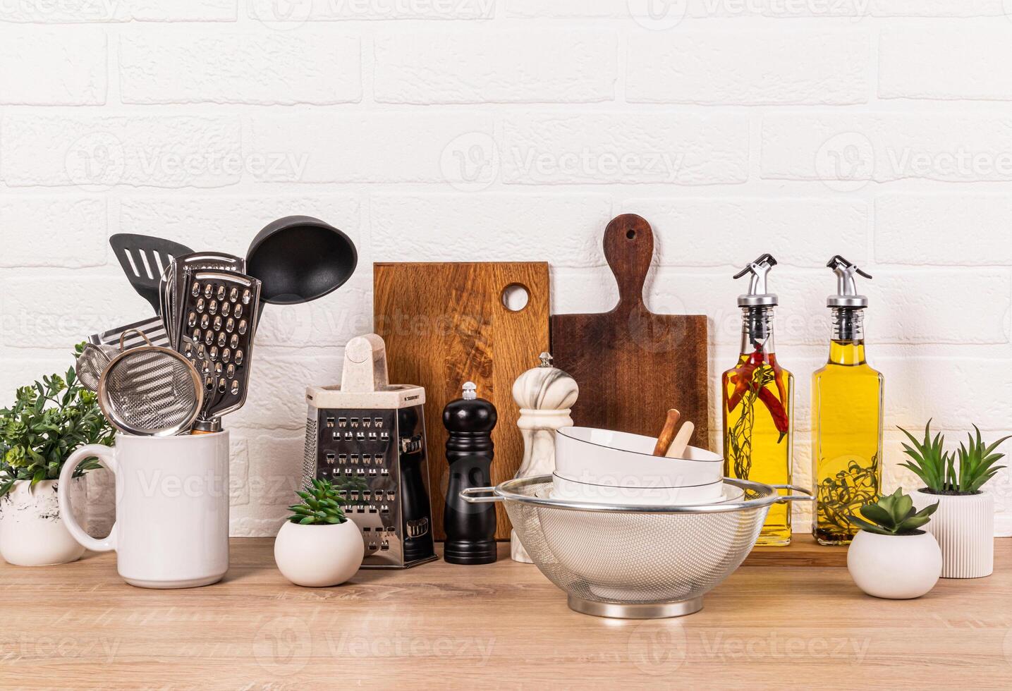 A variety of wooden and metal kitchen utensils on a wooden countertop. Glass bottles with oil in a wooden case. Stylish Storage Area photo