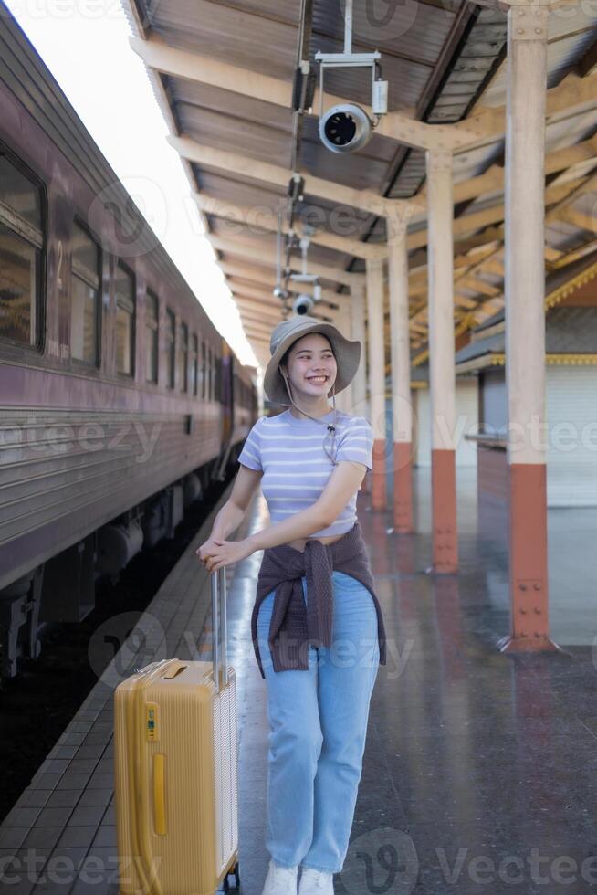 Young woman with suitcase waits at the metro station while the train arrrives, Tourism and travel in the summer. Vacations for the student. Work and travel photo