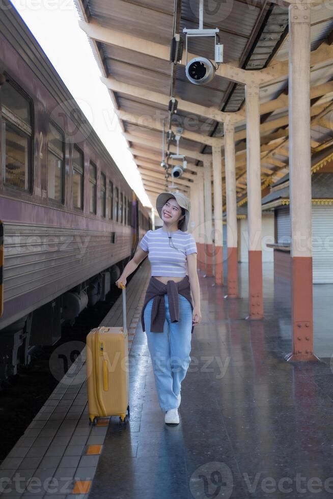 Young woman with suitcase waits at the metro station while the train arrrives, Tourism and travel in the summer. Vacations for the student. Work and travel photo