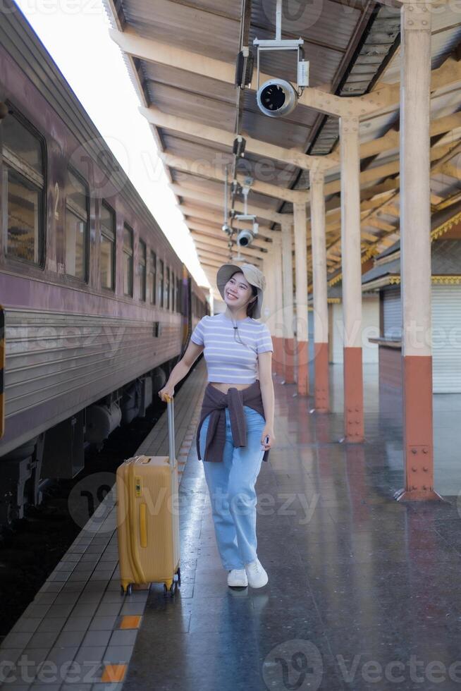 Young woman with suitcase waits at the metro station while the train arrrives, Tourism and travel in the summer. Vacations for the student. Work and travel photo