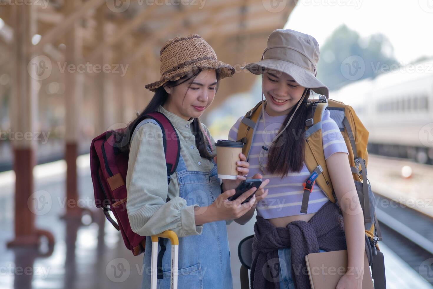 two young asian friends girls with backpacks at railway station waiting for train, Two beautiful women walking along platform at train station photo