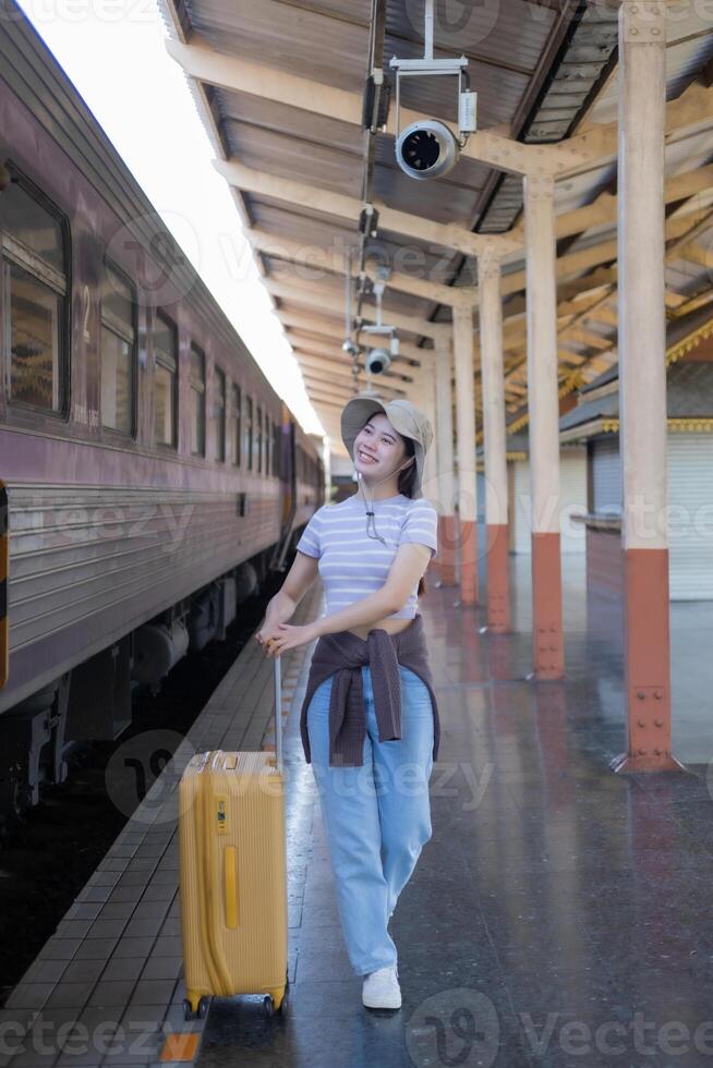 Young woman with suitcase waits at the metro station while the train arrrives, Tourism and travel in the summer. Vacations for the student. Work and travel photo