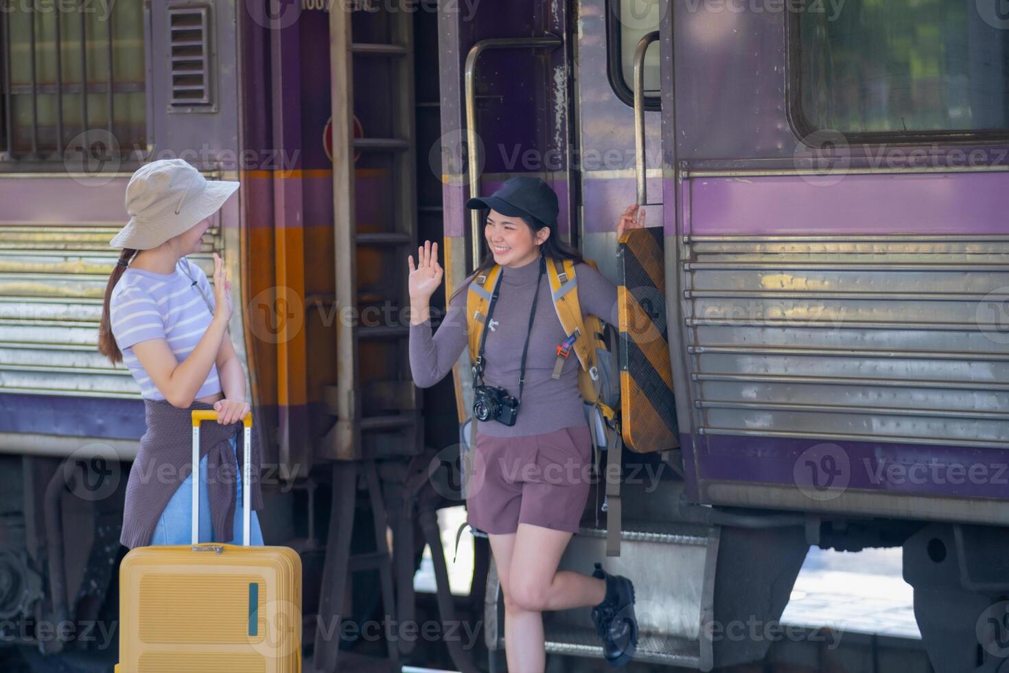 two young asian friends girls with backpacks at railway station waiting for train, Two beautiful women walking along platform at train station photo