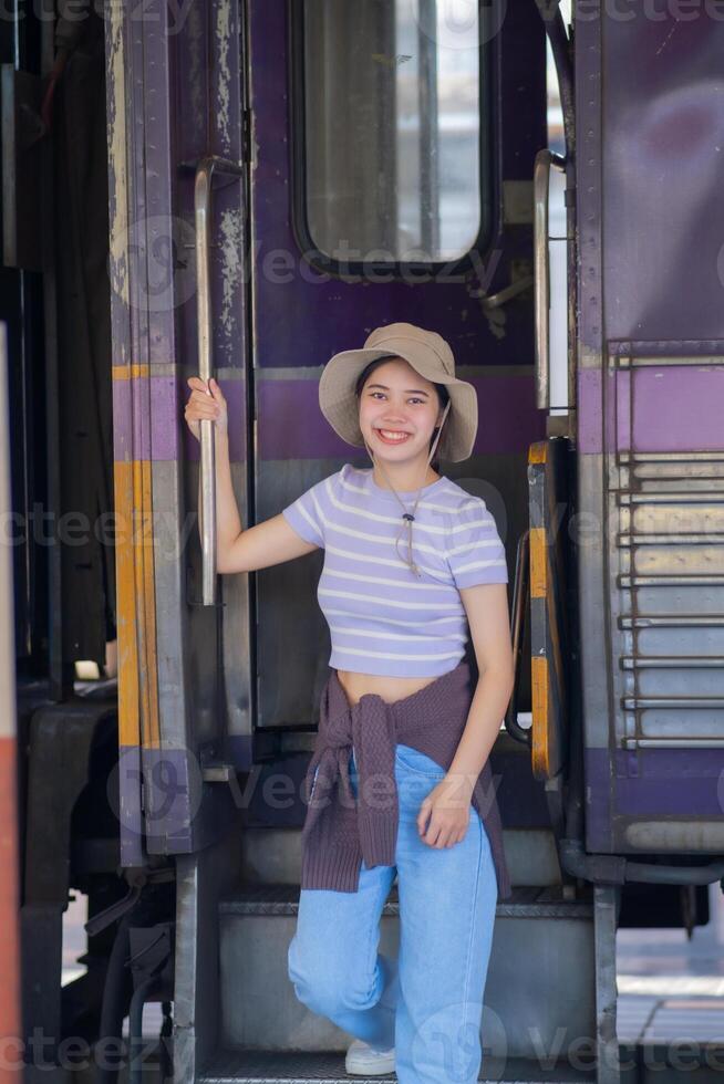 joven mujer con maleta murga a el metro estación mientras el tren llega, turismo y viaje en el verano. vacaciones para el alumno. trabajo y viaje foto