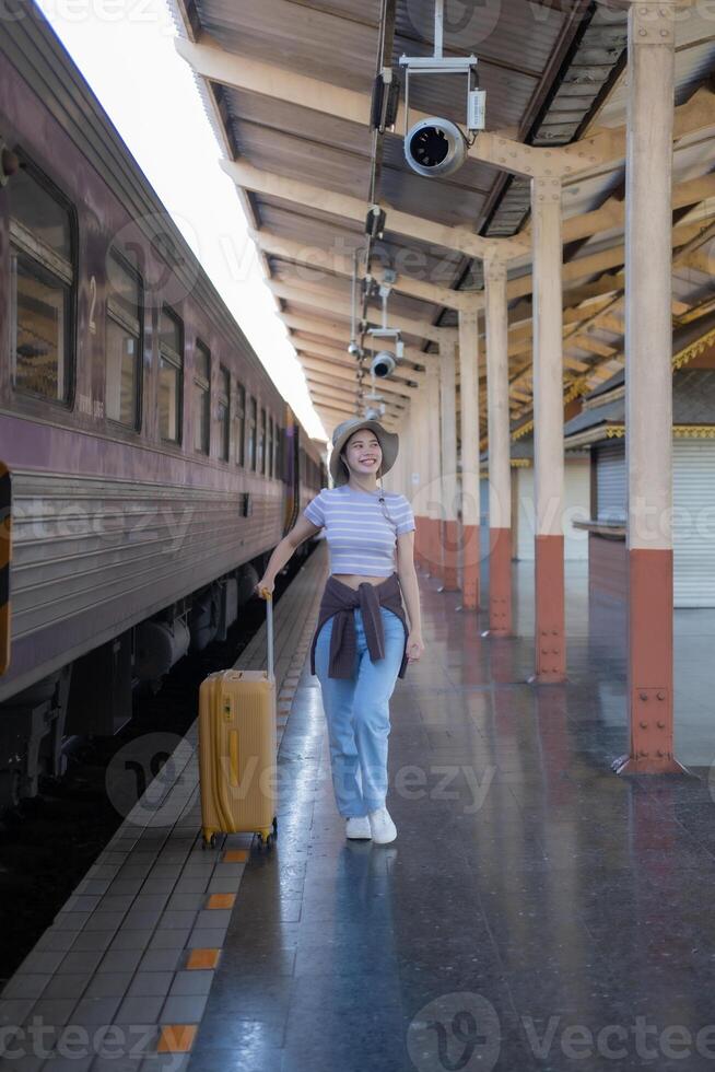 Young woman with suitcase waits at the metro station while the train arrrives, Tourism and travel in the summer. Vacations for the student. Work and travel photo