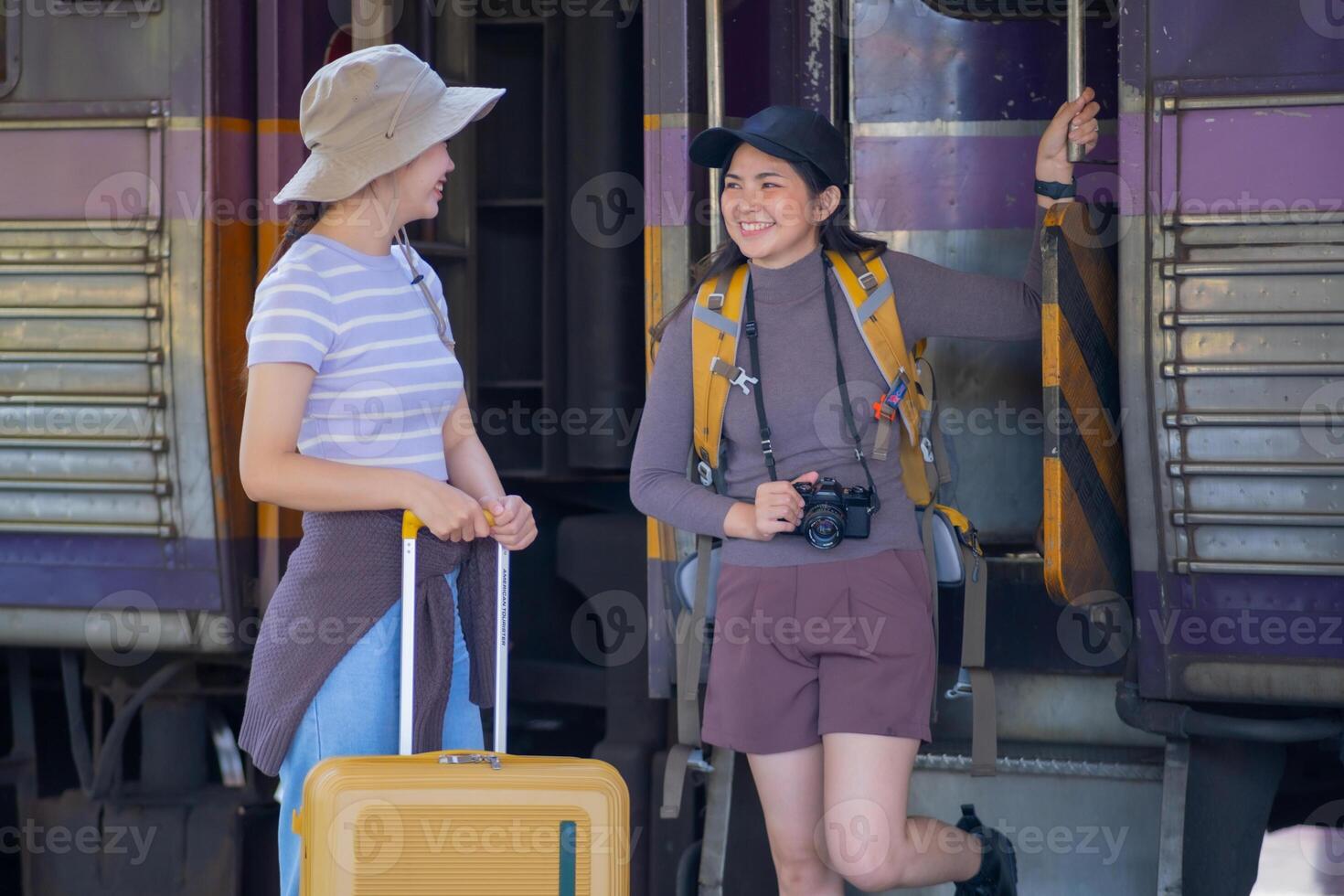 two young asian friends girls with backpacks at railway station waiting for train, Two beautiful women walking along platform at train station photo