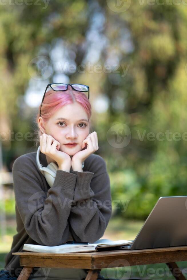 Woman working at the laptop in the backyard with a lot of greenery,  laptop and portrait of woman in park for education photo