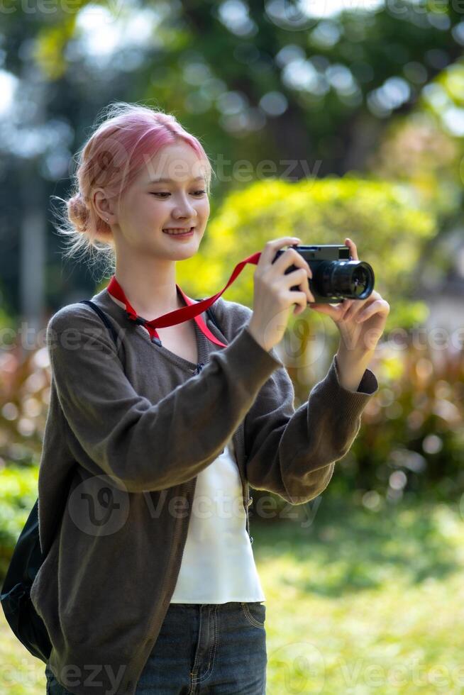 Beautiful Young artist Woman taking photo in flowers garden. Young cute girl carry the camera in the garden