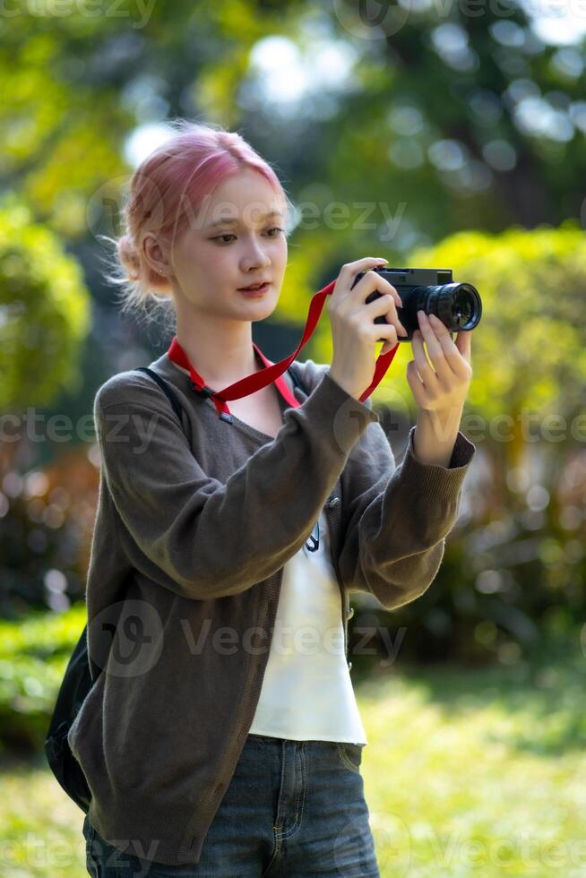 hermosa joven artista mujer tomando foto en flores jardín. joven linda niña llevar el cámara en el jardín