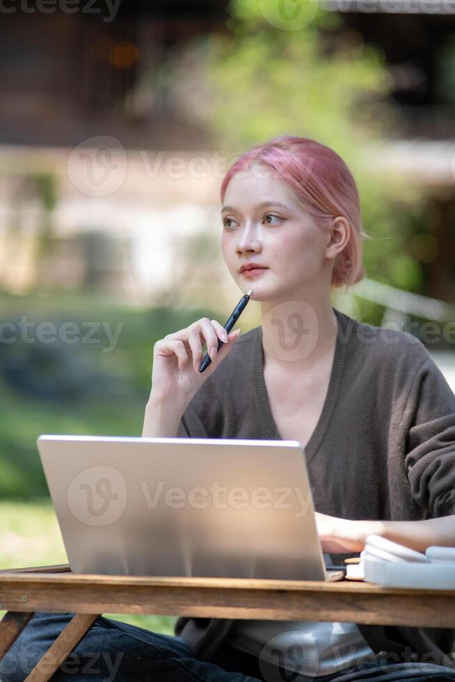 Woman working at the laptop in the backyard with a lot of greenery,  laptop and portrait of woman in park for education photo