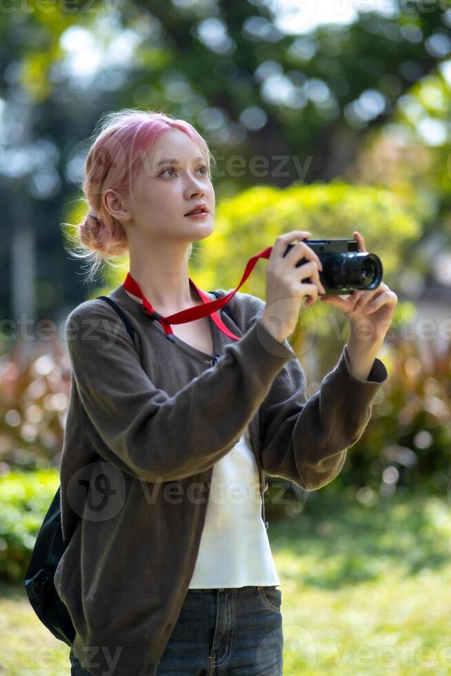 hermosa joven artista mujer tomando foto en flores jardín. joven linda niña llevar el cámara en el jardín