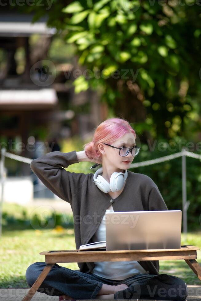 Woman working at the laptop in the backyard with a lot of greenery,  laptop and portrait of woman in park for education photo