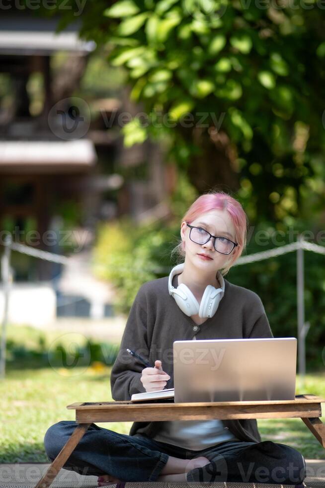 Woman working at the laptop in the backyard with a lot of greenery,  laptop and portrait of woman in park for education photo