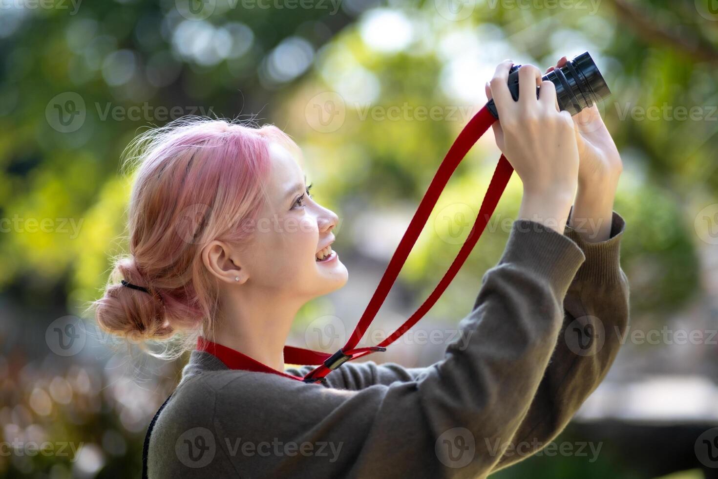 Beautiful Young artist Woman taking photo in flowers garden. Young cute girl carry the camera in the garden