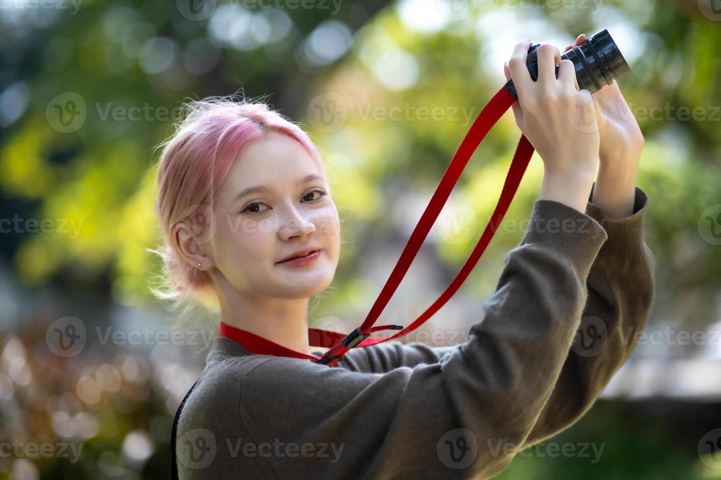 Beautiful Young artist Woman taking photo in flowers garden. Young cute girl carry the camera in the garden