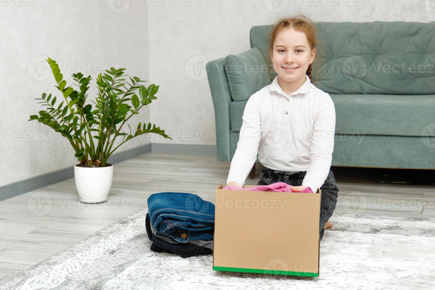 cute girl collects clothes in a box for charity and donation photo