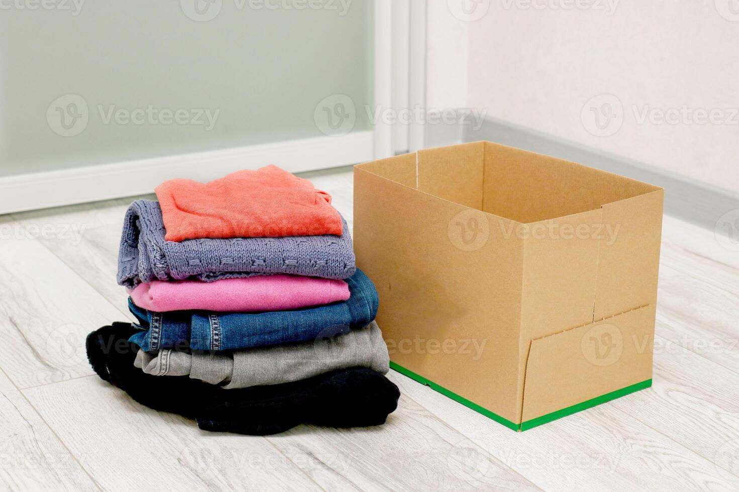 folded clothes next to an empty box on the floor photo