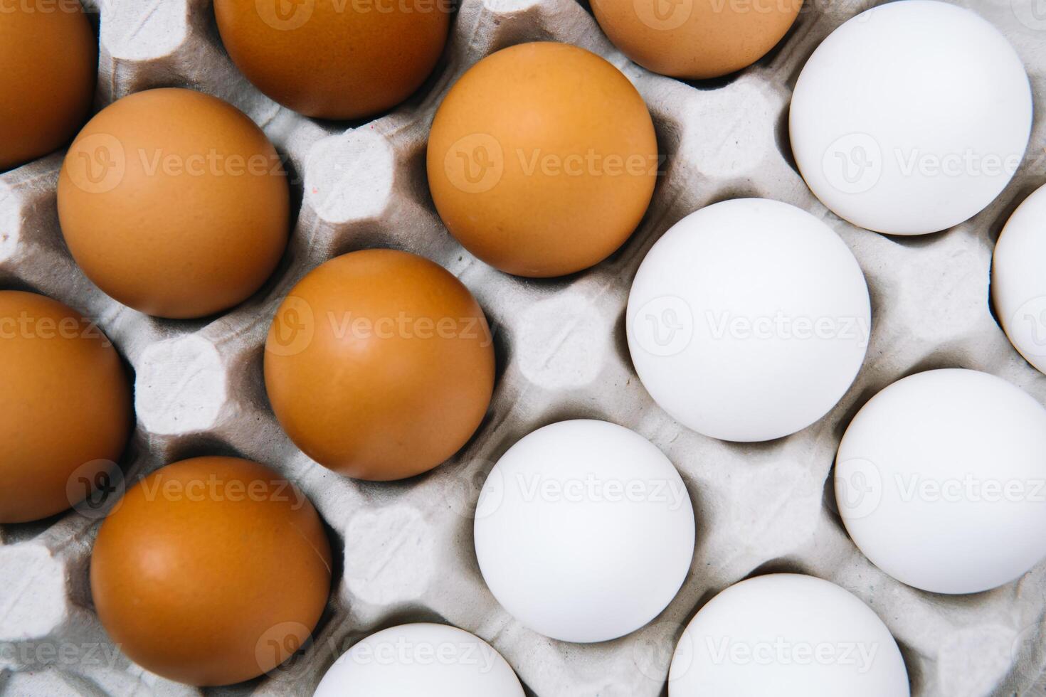 Flat lay of white and brown eggs in egg paper box. Fresh chicken eggs background. Top view natural organic egg. Healthy real food photo