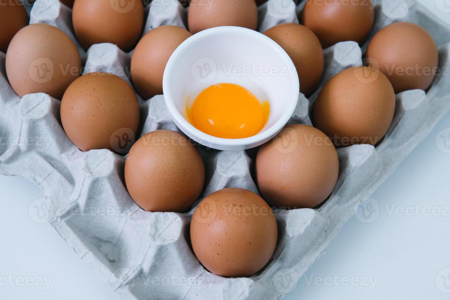 Brown raw chicken eggs and alone broken egg in a tray top view photo