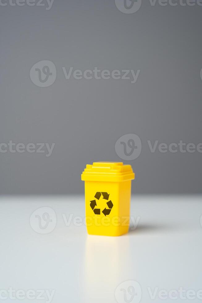 Yellow recycling bin on gray background. Selling recycled material or getting grants for green projects. Circular economy. Conserve natural resources, reduce waste, create jobs in recycling industry. photo