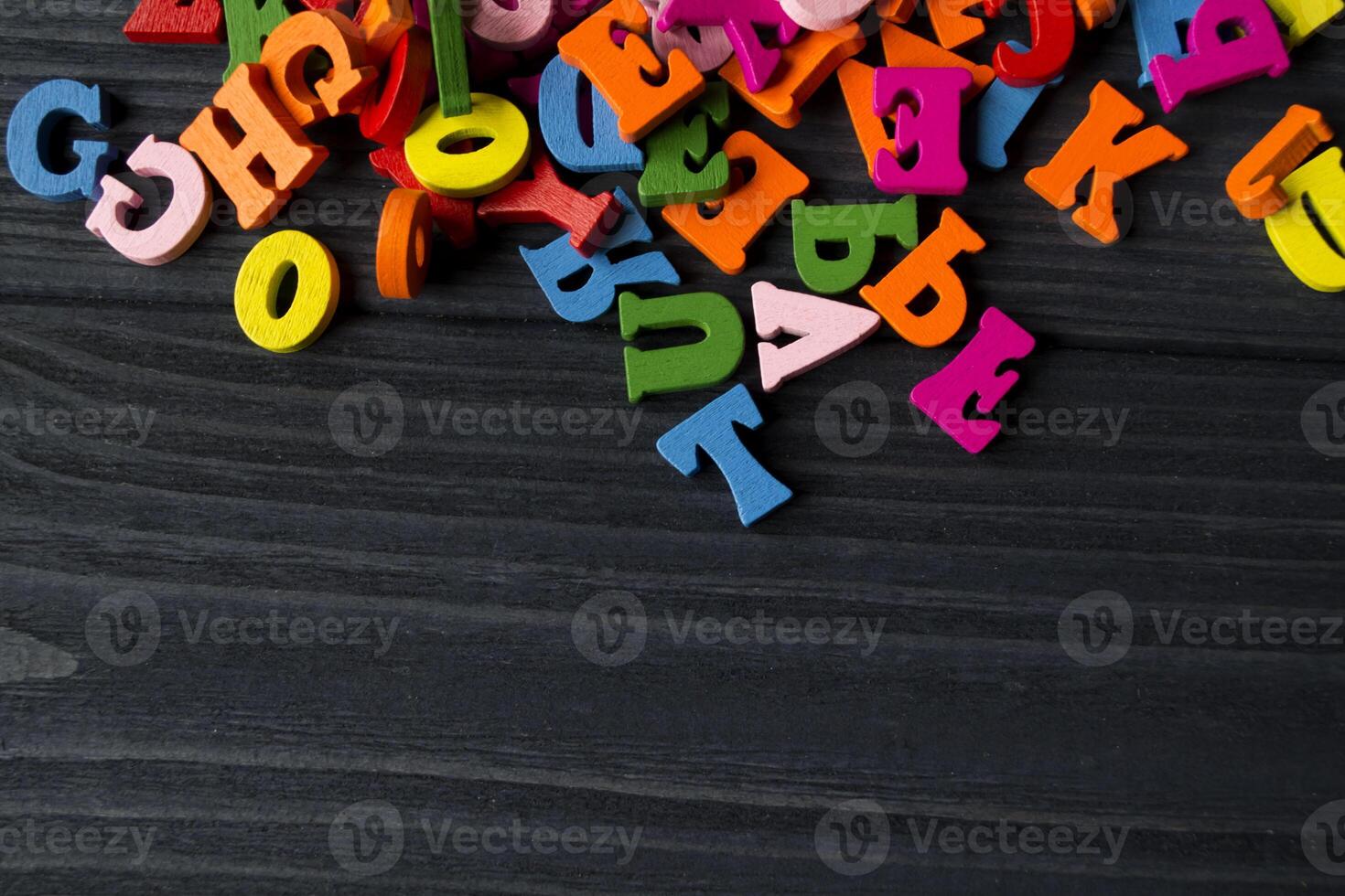 Multicolor letters on a dark blue wooden background. Colorful wooden alphabet on a table. photo