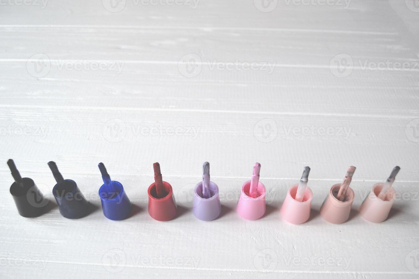 Palette of nail polish on the white wooden background with place for text. Manicure salon. photo