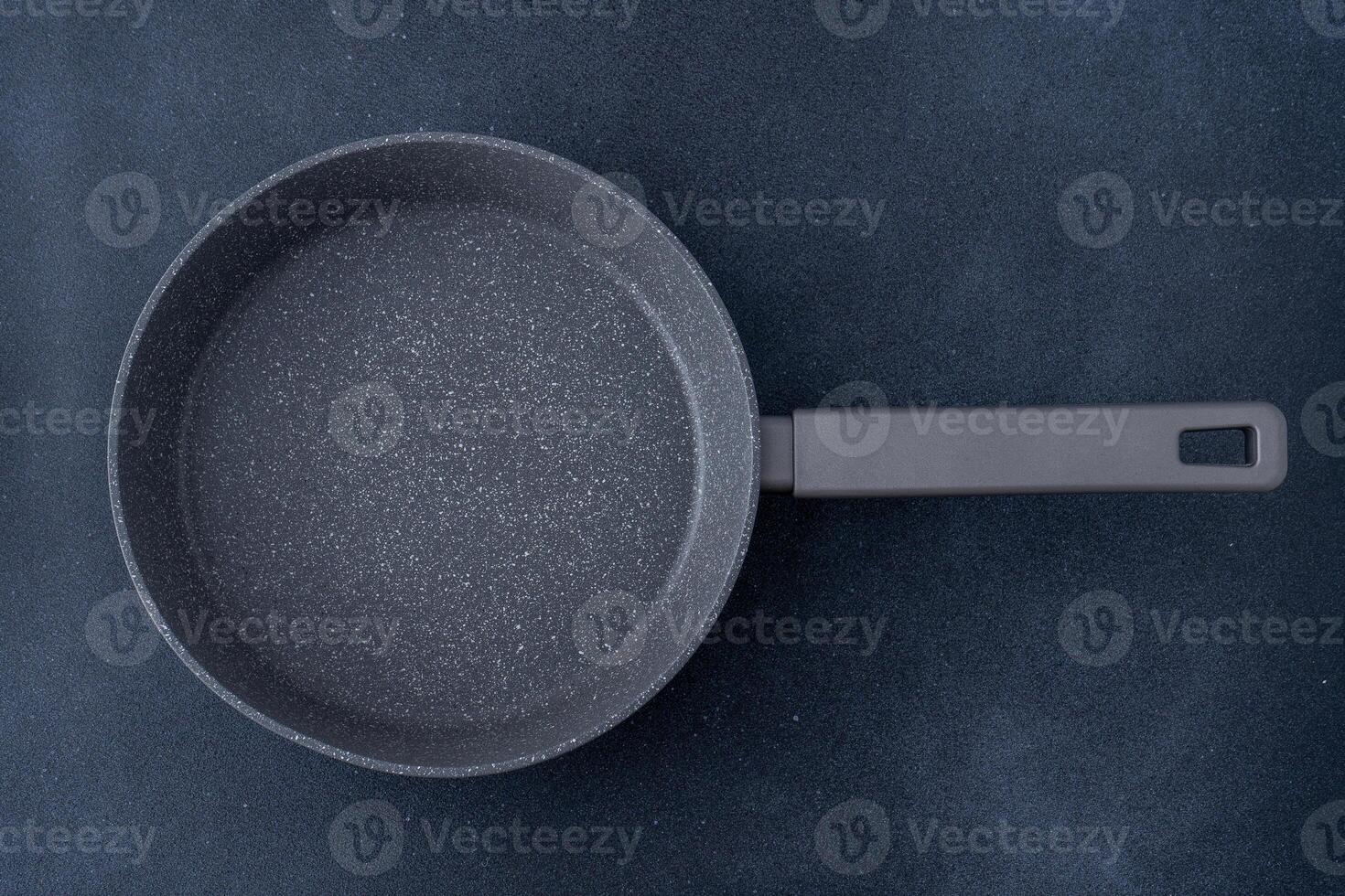 New granite frying pan on a gray background, top view. Empty fry pan with handle. photo