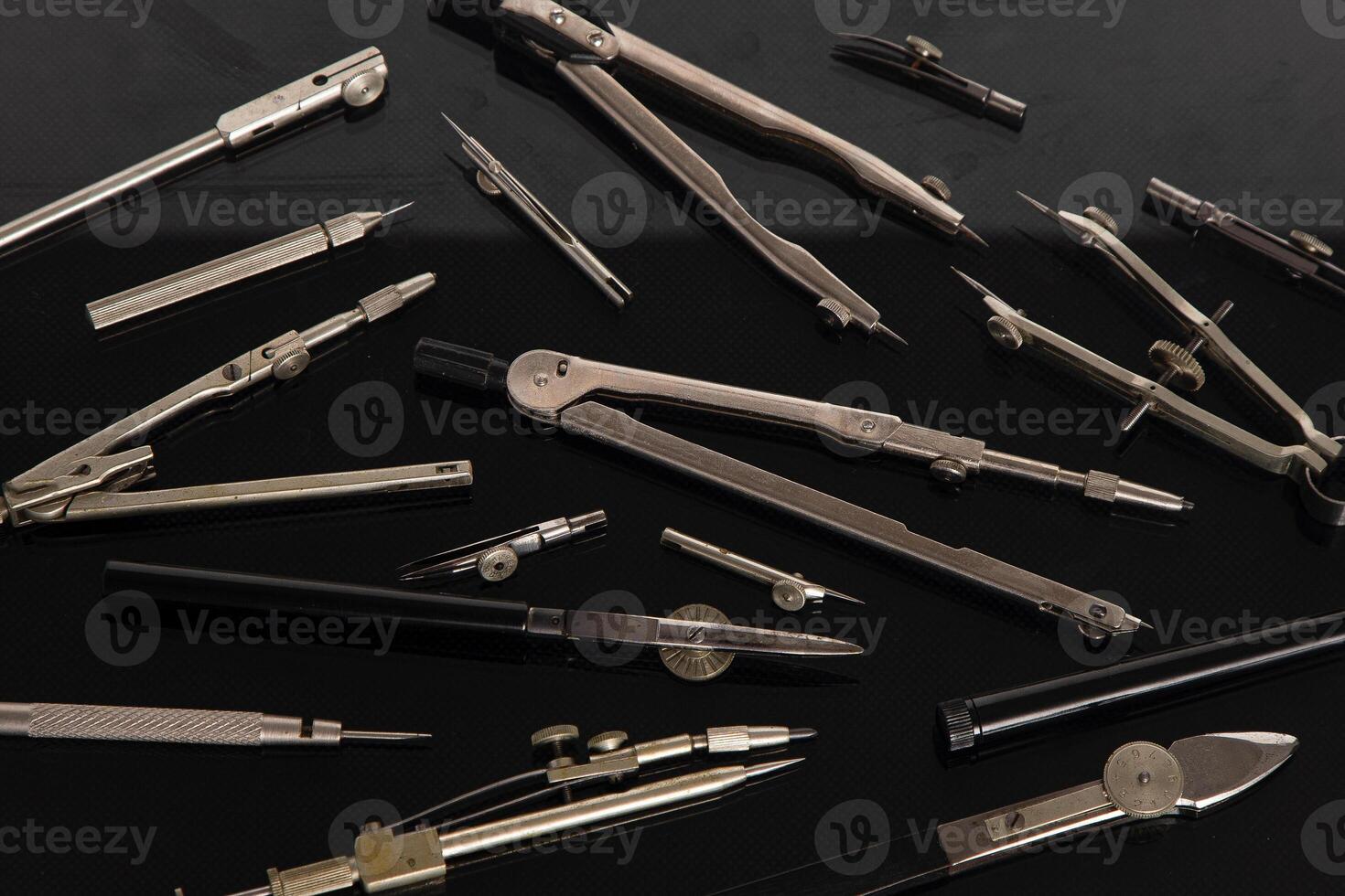 Set of old different compasses. Retro metal compasses and drafting tools on a black background. Drawing pen. photo