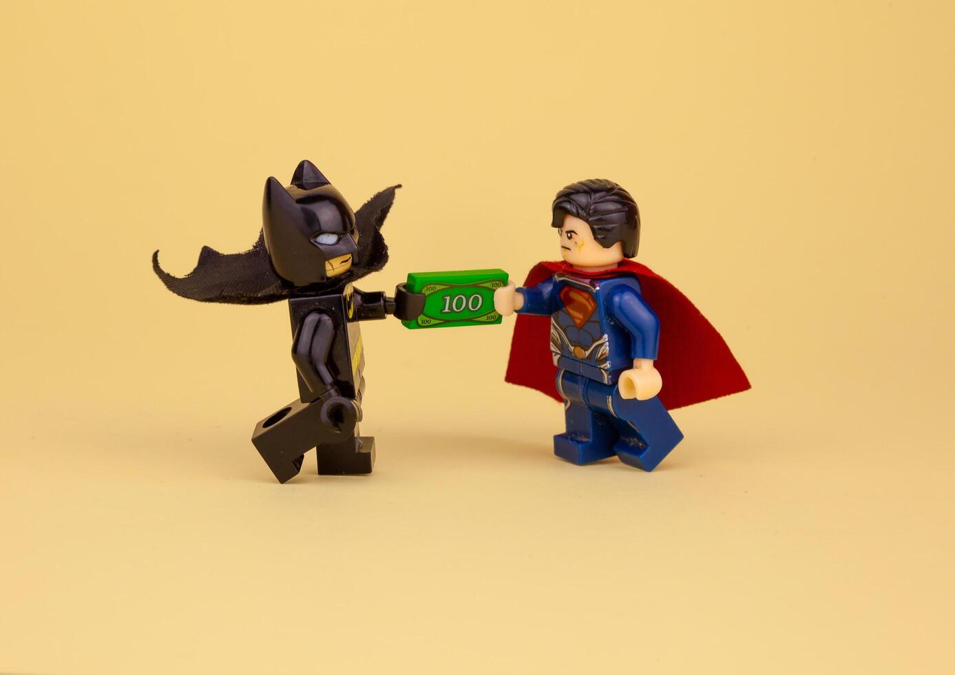 Ukraine, Kyiv - April 6, 2020 lego minifigures. Batman gives Superman a hundred dollars. Get paid in cash. To give a bribe photo