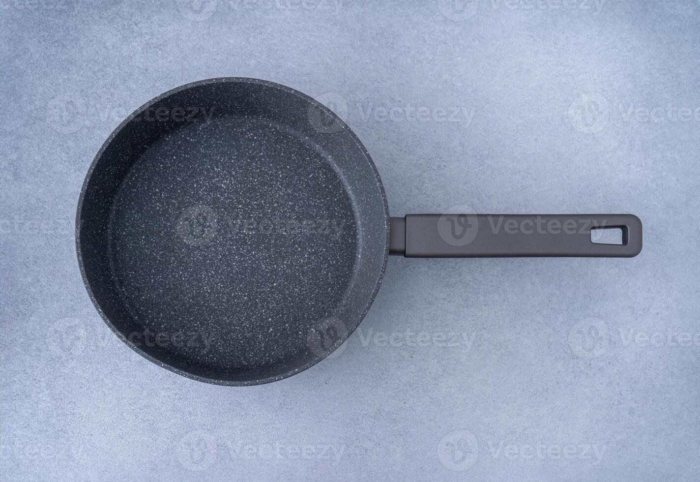 New granite frying pan on a gray background, top view. Empty fry pan with handle. photo