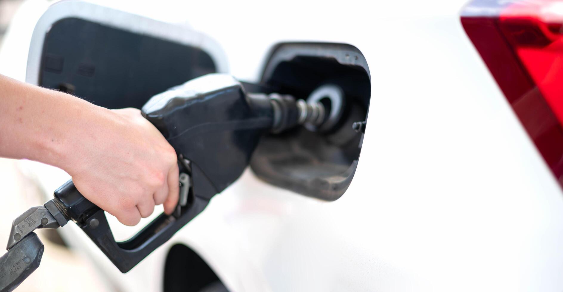 Female worker choose the type of oil gas at pump gas station photo