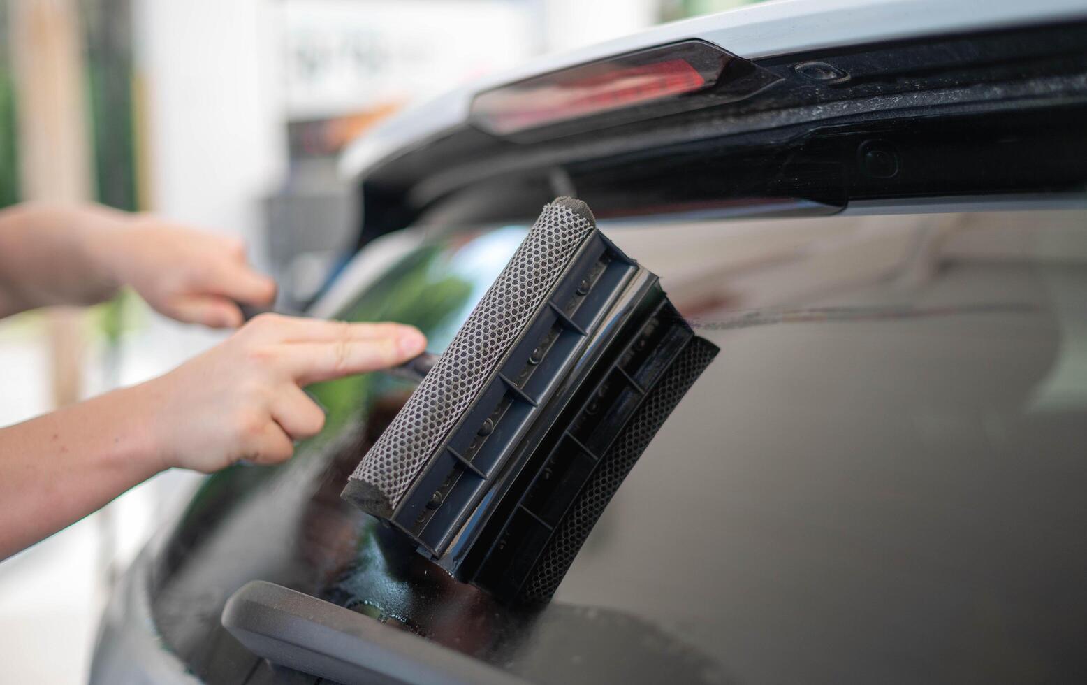 Mature male worker cleaning car windshield with the sponge mop. photo