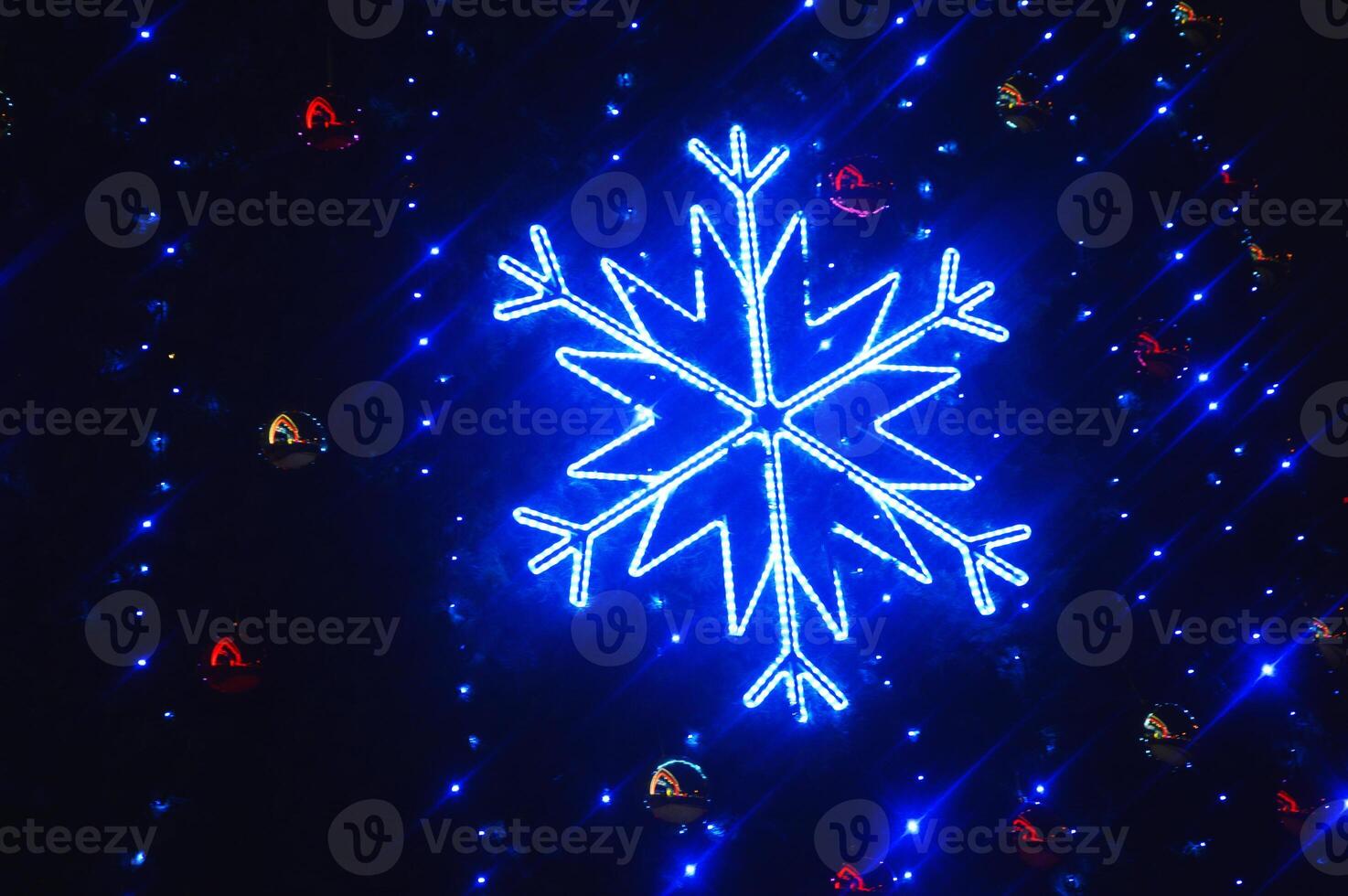 Beautiful large blue decorative shiny glowing snowflake on a dark background. Evening festive Christmas illumination. photo