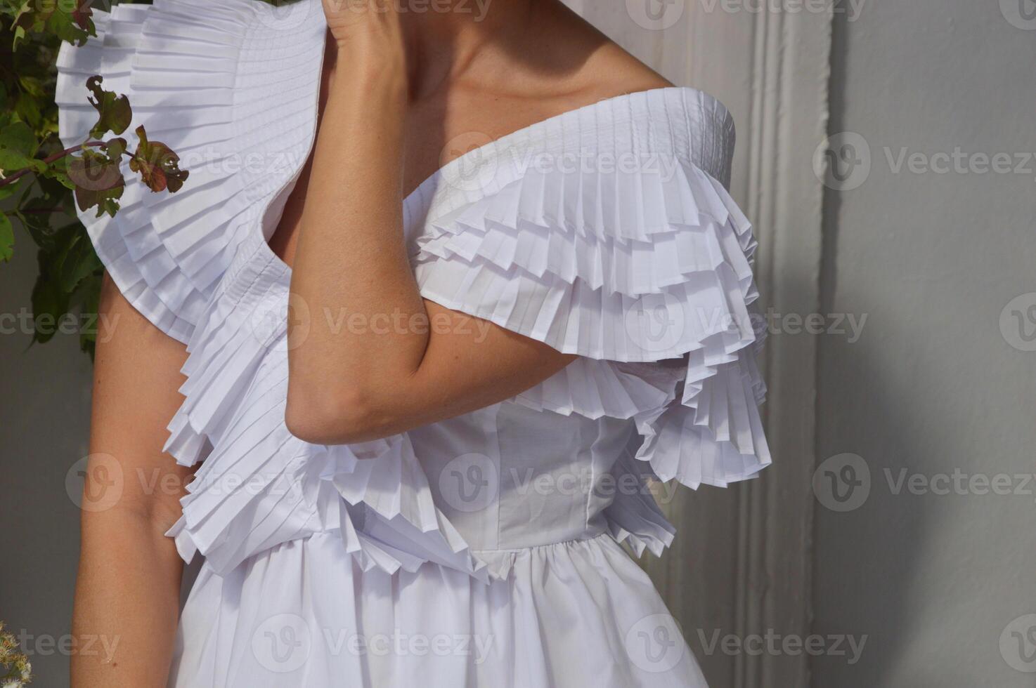 Girl, woman bride dressed in a white dress on a gray background. Fashionable wedding dress with stylish puffy sleeves and neckline. photo